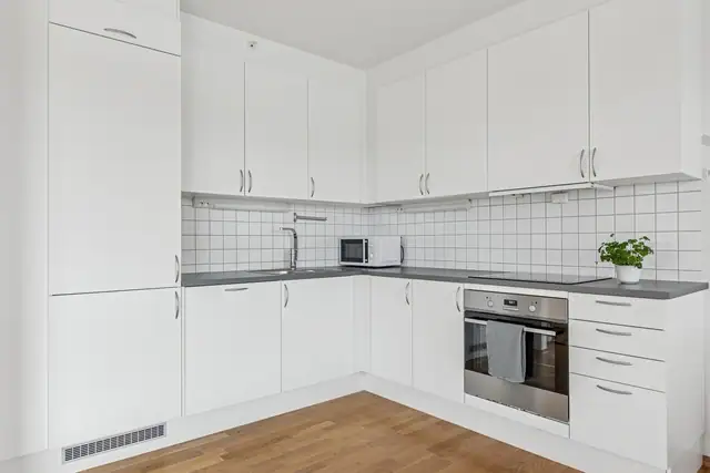 Lys kjøkkeninnredning med integrerte hvitevarer.