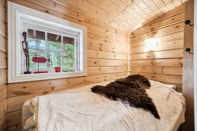 Sjarmerende rom med lune trevegger og myke tekstiler. Rommet er innredet med en komfortabel seng, og vinduet slipper inn naturlig lys med utsikt mot skogen.