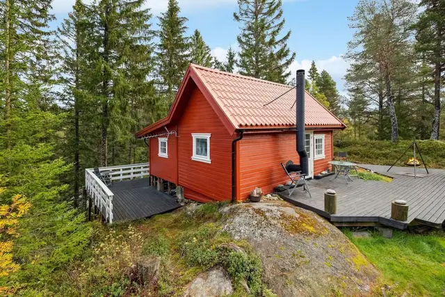Klassisk hytte med utendørs terrasse, omkranset av skog for ekstra privatliv.
