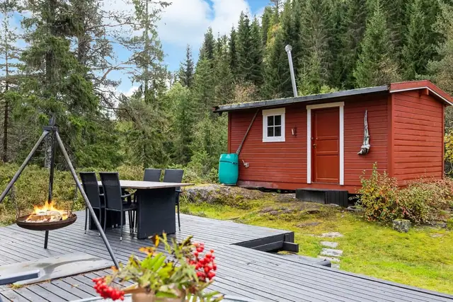 Romslig terrasse med plass til avslapning, omkranset av frodig natur og skog som skaper en rolig atmosfære.