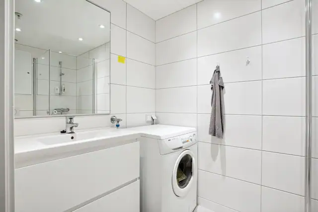 Badet er praktisk innredet med servant med store oppbevaringsskuffer i underkant, innfellbart dusjhjørne, vegghengt klosett og vaskemaskin.
