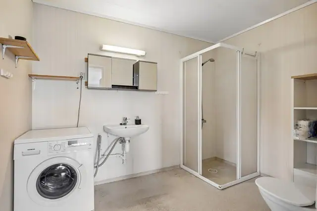 Badet har opplegg for vaskemaskin, dusjhjørne, servant og toalett.