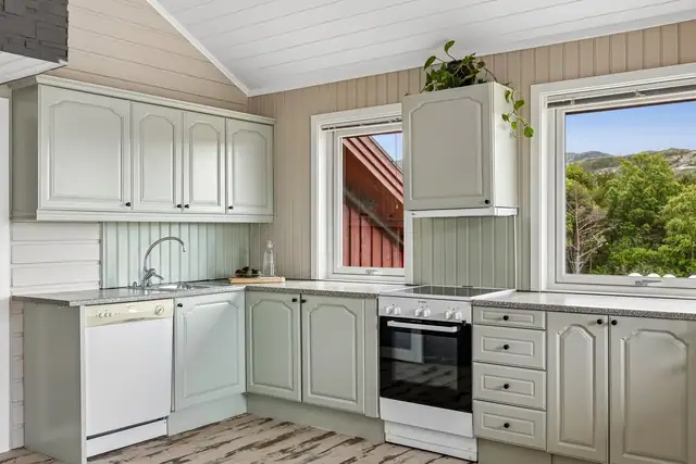Kjøkken er innredet med profilerte fronter, frittstående komfyr, oppvaskmaskin og kjøleskap med fryser.