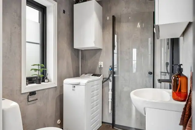 Badet har moderne stil med baderomsplater på vegg og baderomsbelegg på gulv.