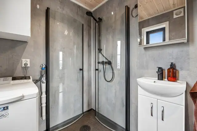 Badet er utstyrt med dusjhjørne, servantinnredning, toalett og opplegg for vaskemaskin.