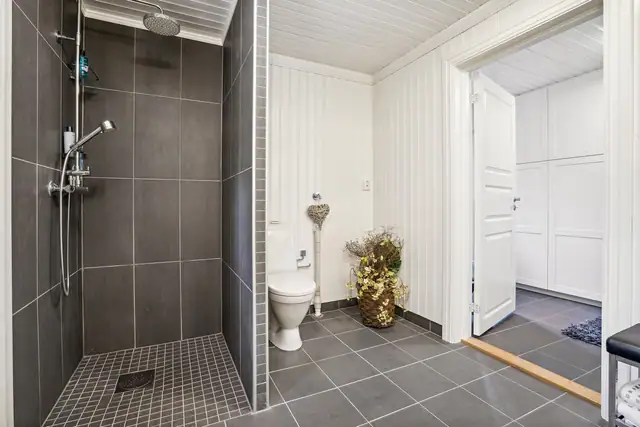 Et meget romslig bad med dusjhjørne og opplegg til vaskemaskin.