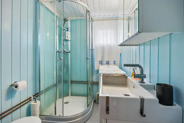 Badet er innredet med servant, toalett og dusjkabinett.