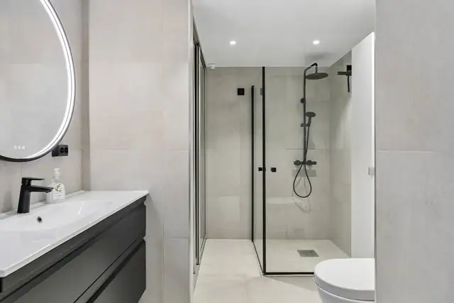 Badet har moderne belysning og delikate fliser som skaper et behagelig og innbydende miljø.