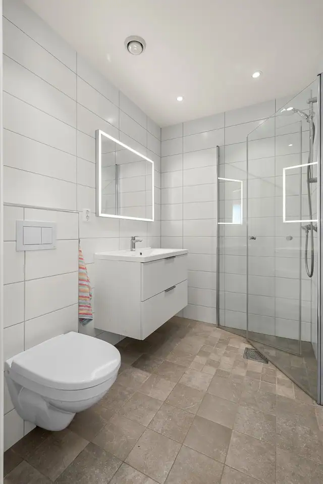 Badet er flislagt med gulvvarme og har en praktisk og moderne utforming.