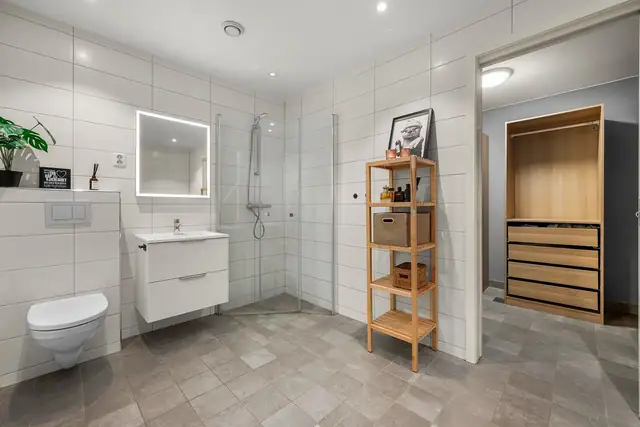 Badet i underetasjen er innredet med flislagt gulv og vegger, dusjhjørne med dører og eget opplegg for vaskemaskin.