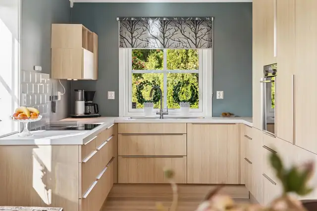 Kjøkkenet fremstår moderne og stilrent med glatte fronter og benkeplate i laminat - en praktisk og innbydende løsning som gjør matlagingen til en fornøyelse.