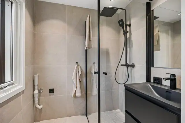 Badet er innredet med dusjløsning, servantinnredning og gjennomførte materialvalg.