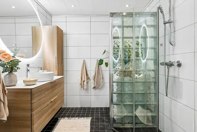Badet måler 6 kvm, og er lagt med flis på gulv og vegger, samt gulvvarme og downligts i himling.