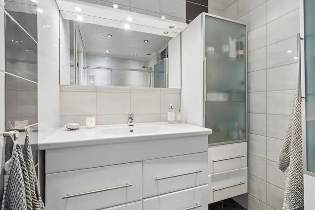 Badet har en praktisk utforming med servantinnredning, toalett og separat dusjnisje med glassvegg.