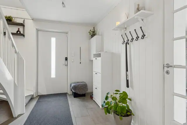 Innbydende entré med flislagt gulv, behagelig gulvvarme og praktisk plass til oppbevaring av yttertøy.